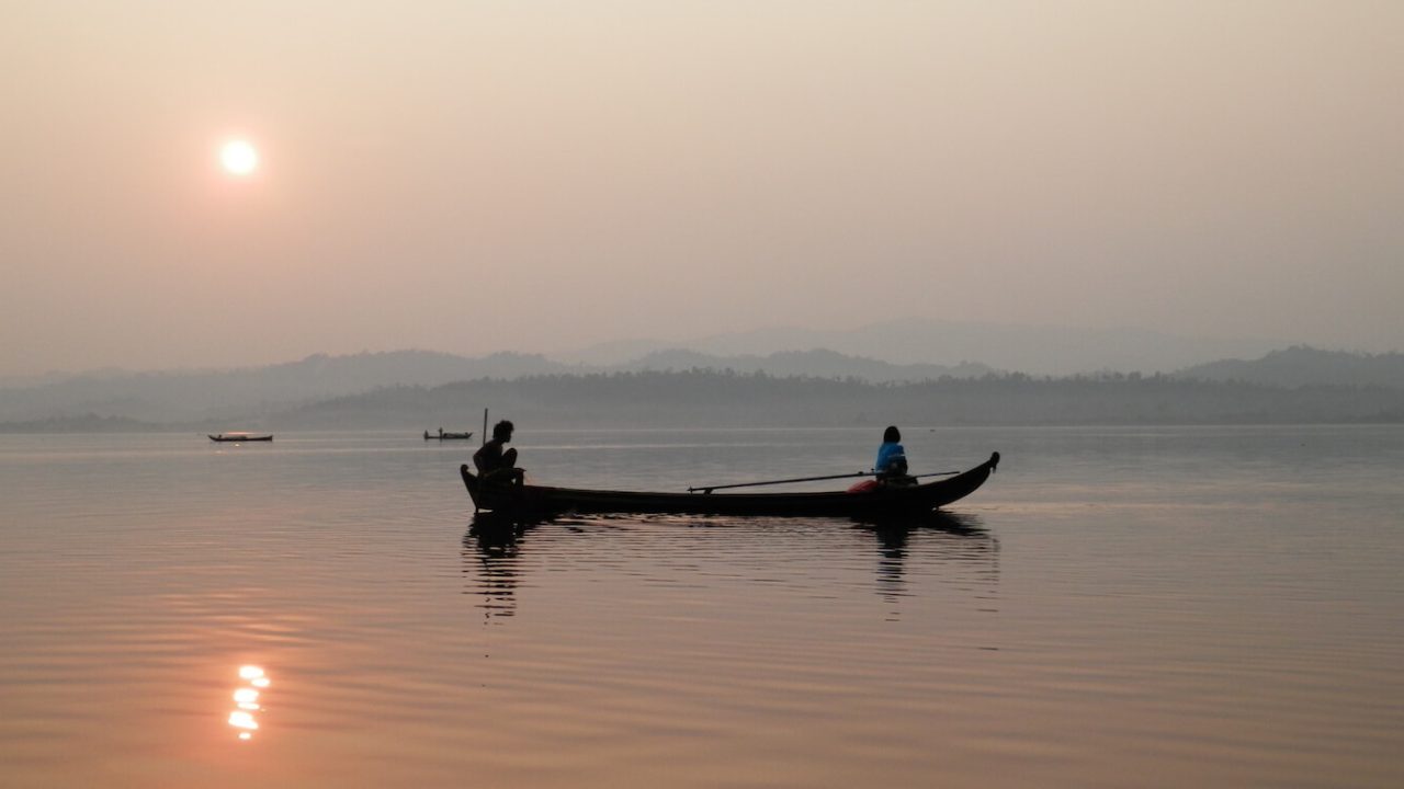 Canoe with two people at sunrise or sunset.