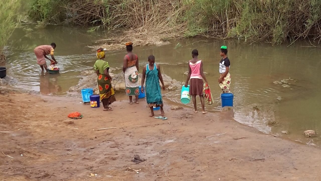 Six women washing laundry along the riverside.