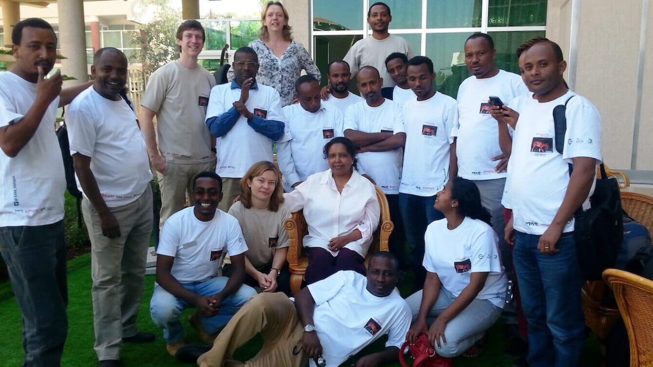 Group of about 20 people posing outside for photo.
