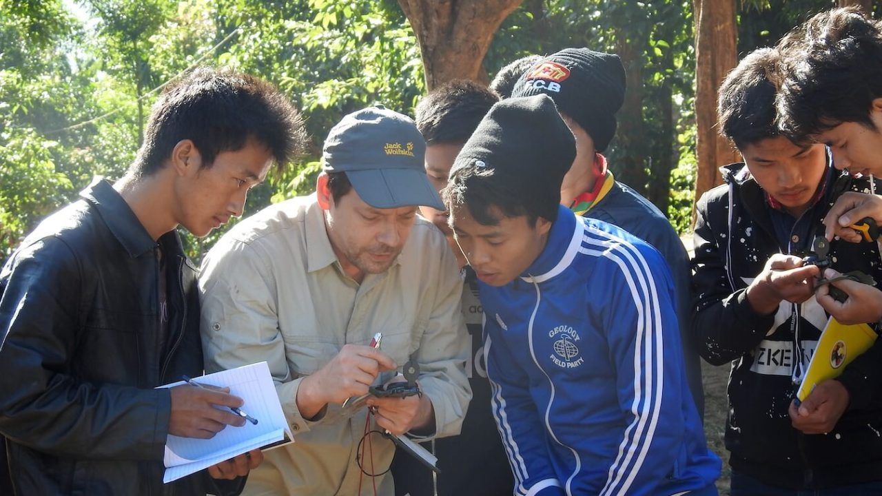 Group of about 7 looking at a handheld monitoring device.