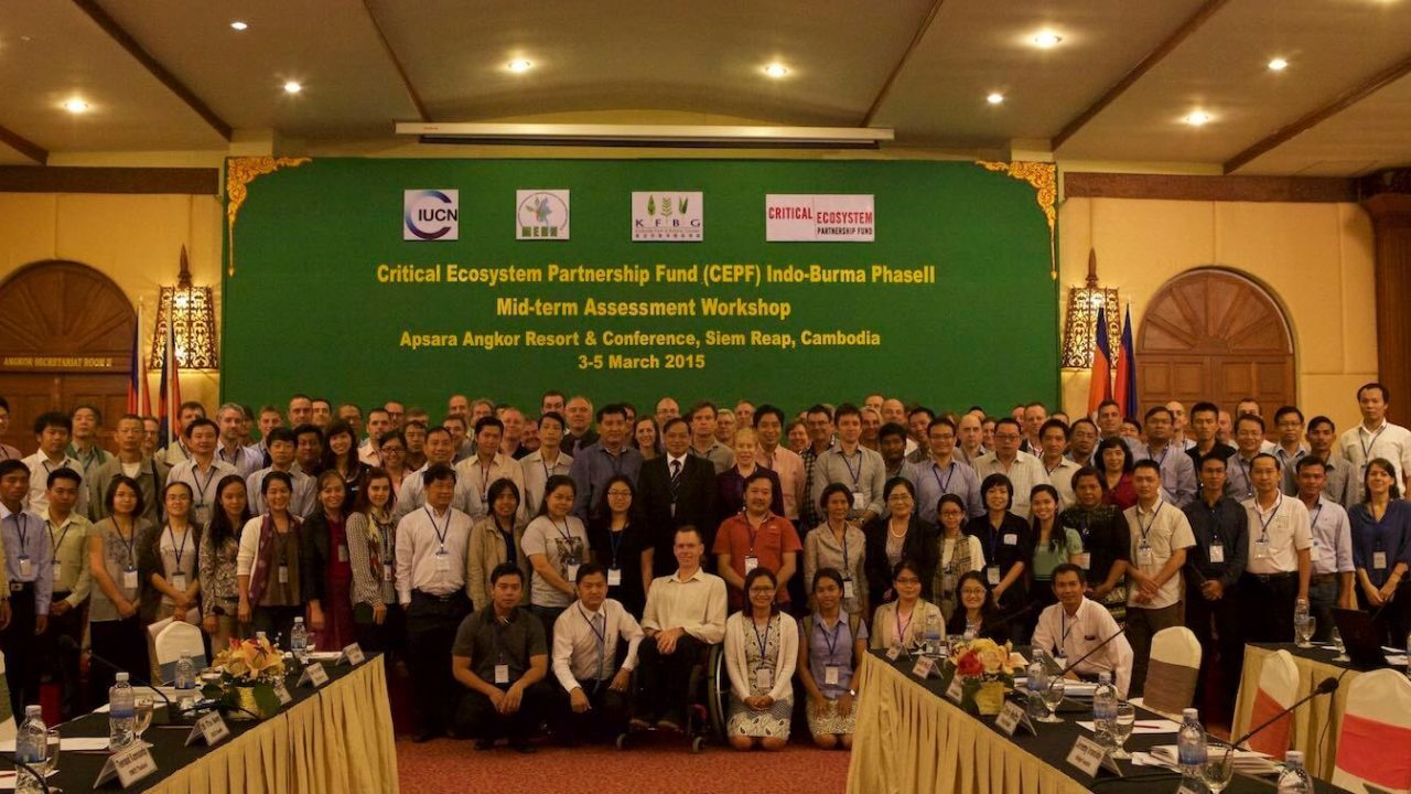 Large group of people pose for photo in conference room.