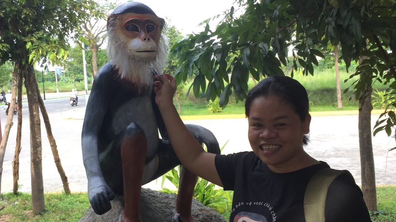 Smiling woman next to 4-foot tall statue.