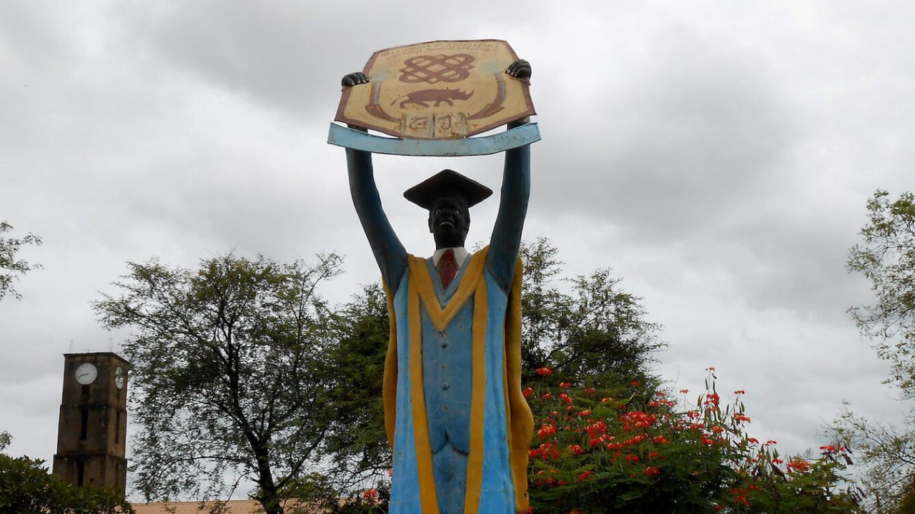 Large statue of graduate holding up sign.