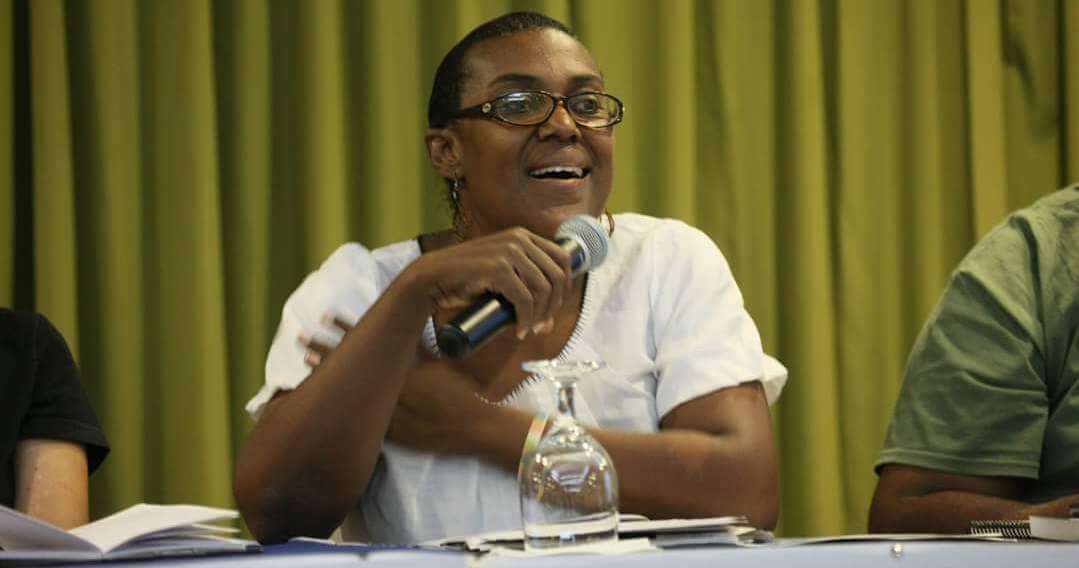 Ingrid sitting at panel table, smiling and speaking into microphone.