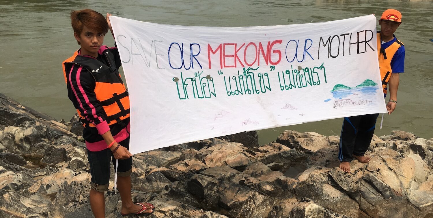 Two boys, about 12-years-old, hold banner with message "Our Mekong, Our Mother"