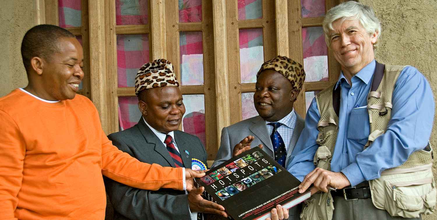 Photo of Russ Mittermeier handing a book on the world's biodiversity hotspots to officials in the Democratic Republic of Congo