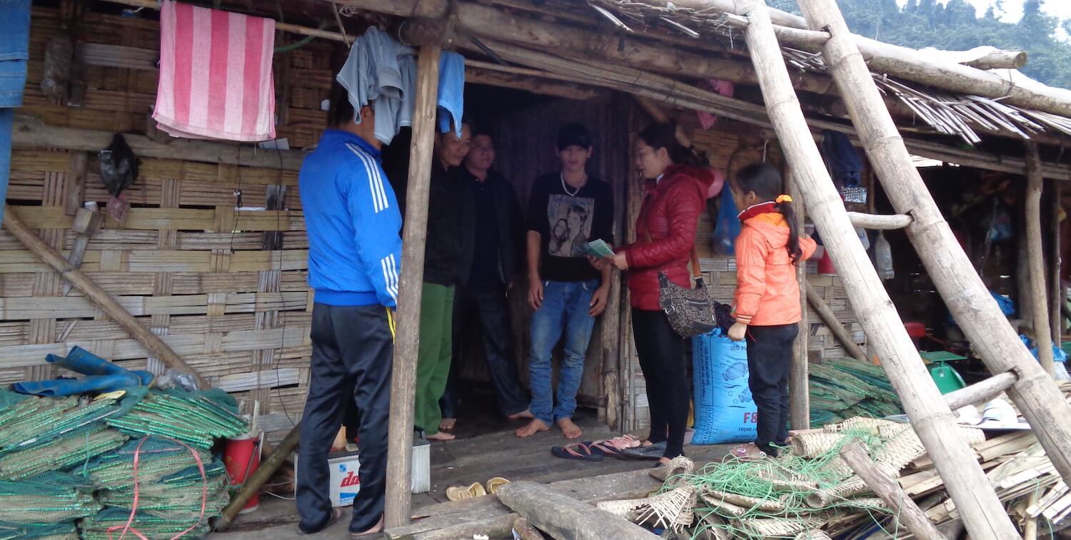 Woman stands in front of doorway, a few other people stand around her.