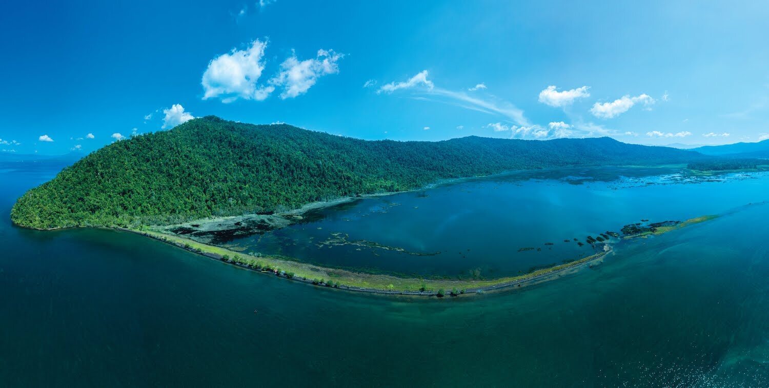 Aeriel view of green mountain range and water.
